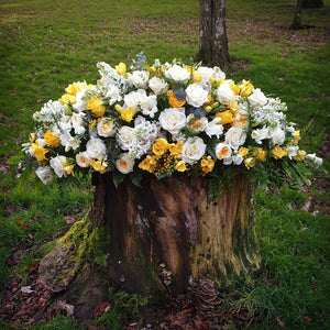 Coffin spray filled with white and yellow roses and freesia